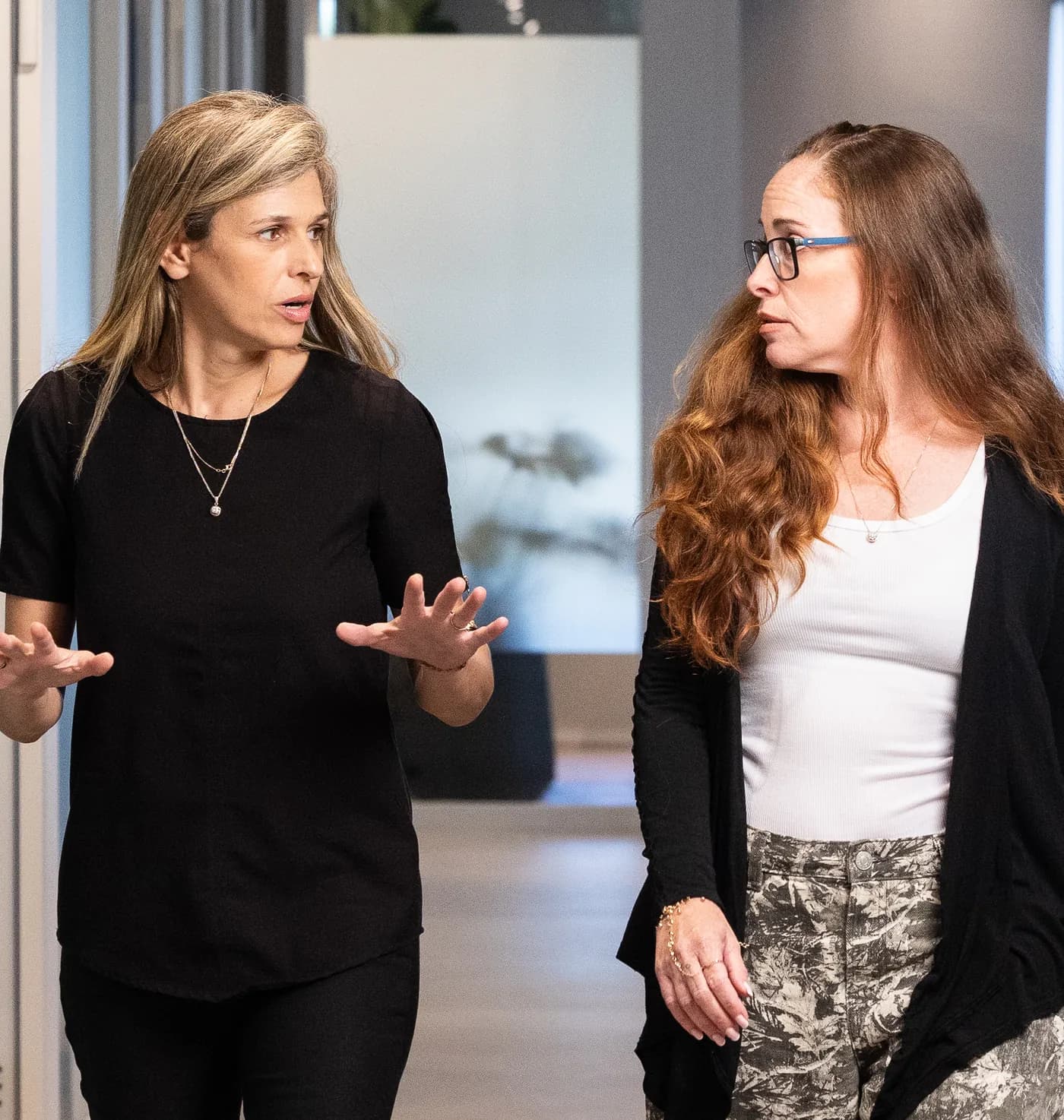 Two colleagues walking and talking in a firm corridor.